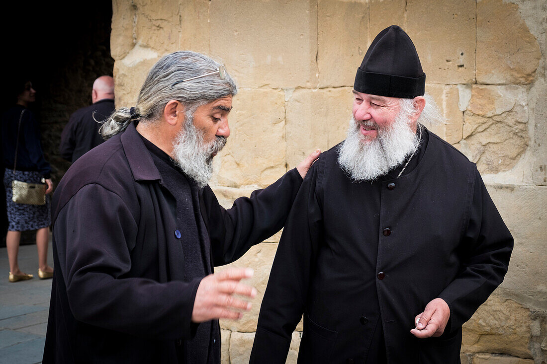 Zwei Menschen sprechen außerhalb der Swetizchoweli-Kathedrale in Mzcheta, Georgia, Caucaus, Eurasien