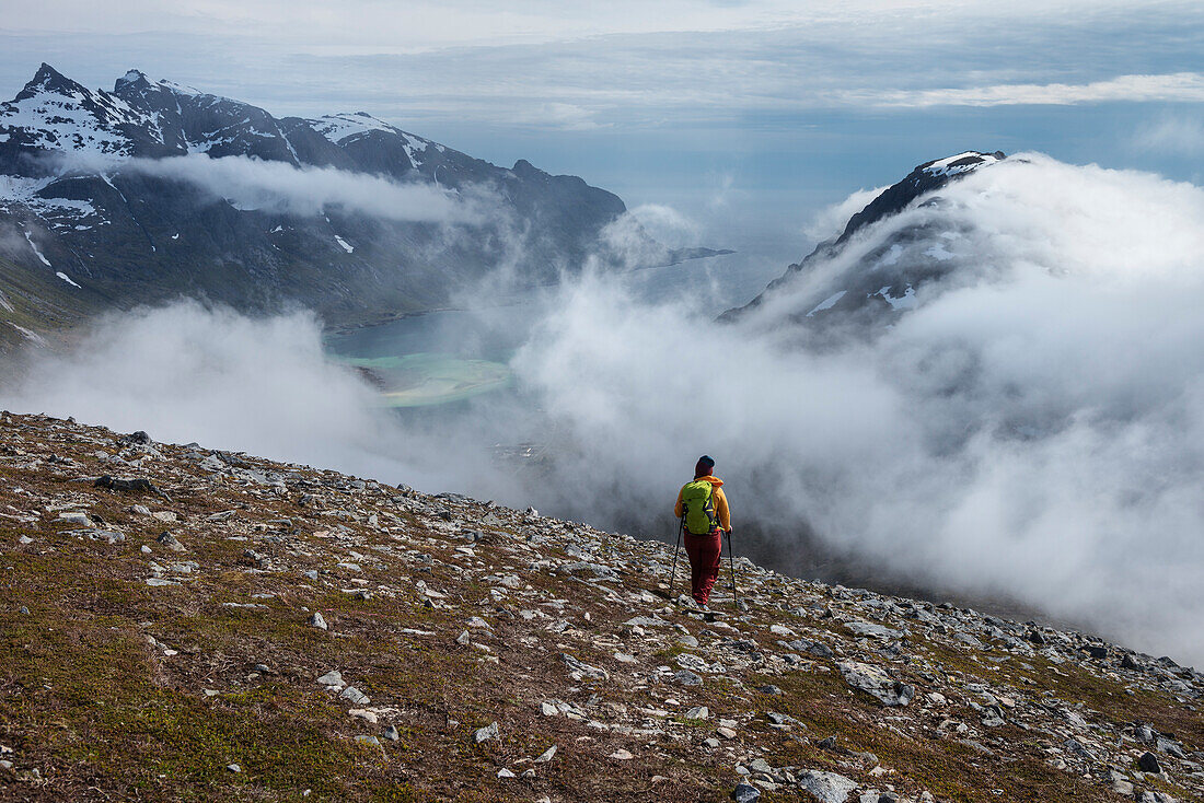 Female hiker hiking in cloudy weather while descending from summit of Volandstind mountain peak, Lofoten Islands, Norway