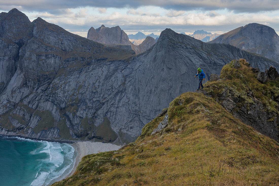 Female hiker walks along narrow ridge near Storskiva mountain peak, MoskenesÃ¸y, Lofoten Islands, Norway