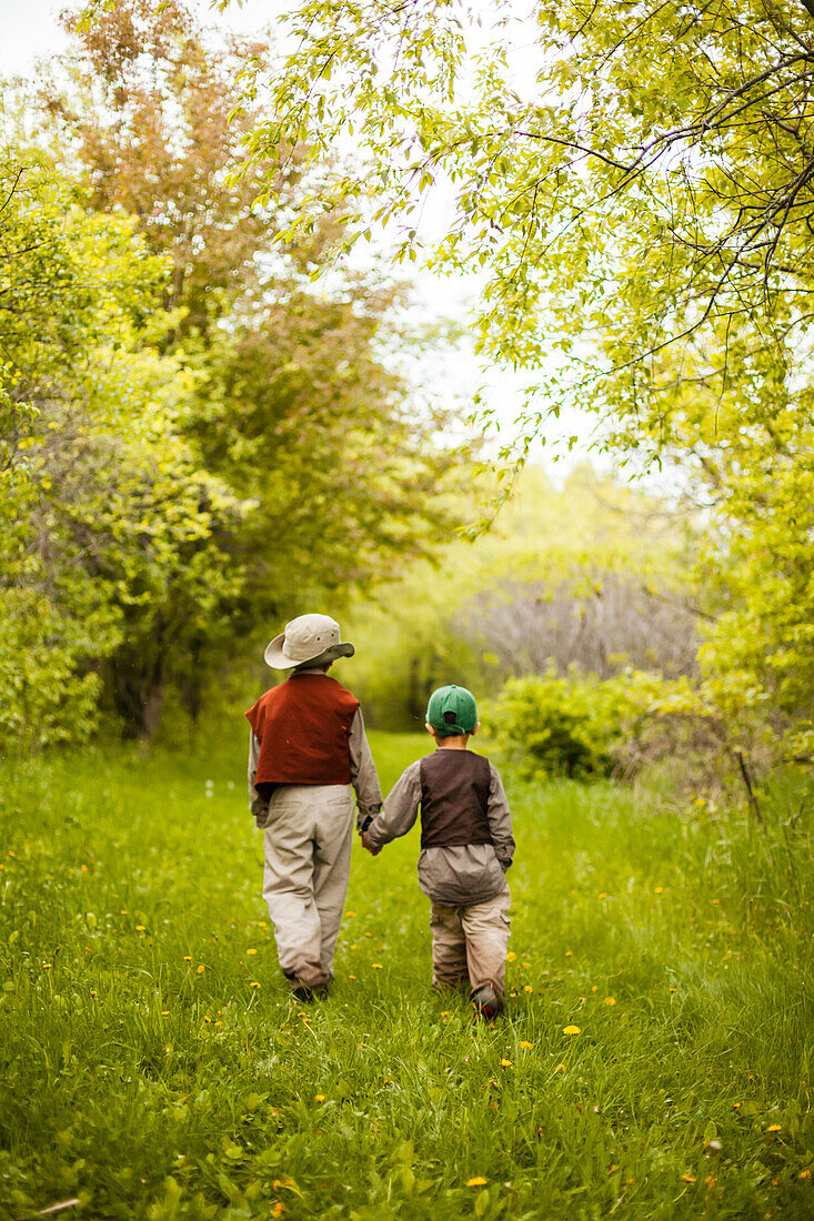 A 6 year old Japanese American boy and his 4 year old Japanese American brother walk through the grassy trails of Myre Island State Park.