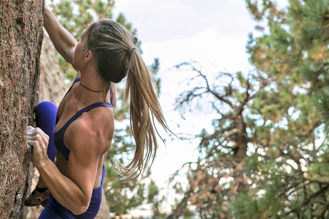 Strong female climber on an outdoor boulder in Colorado