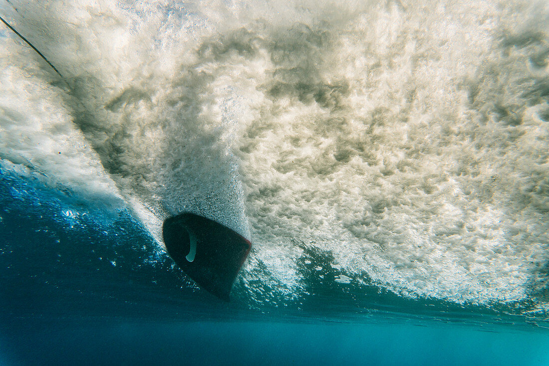 Unterwassersicht einer Welle und eines Surfers auf einer Sonnenaufgangssitzung