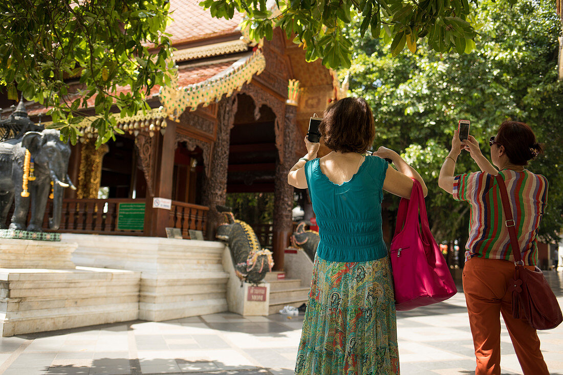 Tourists photograph one of buildings at Wat Phra That Doi Suthep in Chiang Mai, Thailand