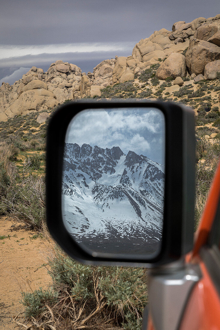 View of mountains in snow in car mirror, California, USA