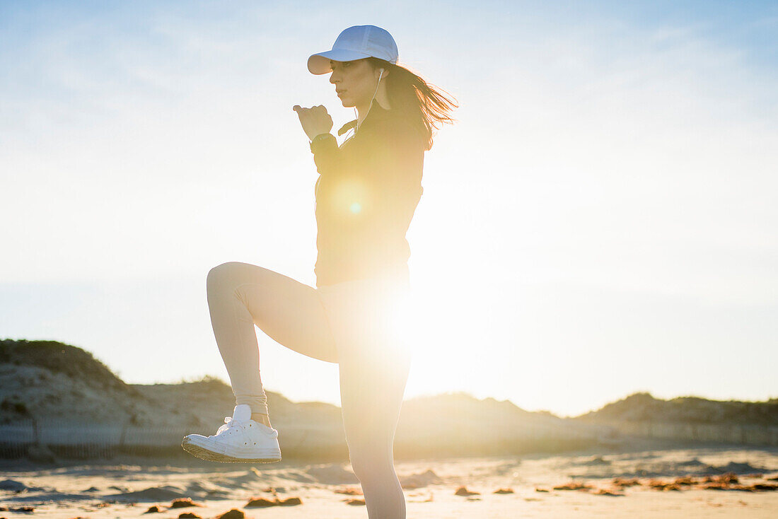 Woman in her twenties working out during an early morning on the beach in Newport, Rhode Island