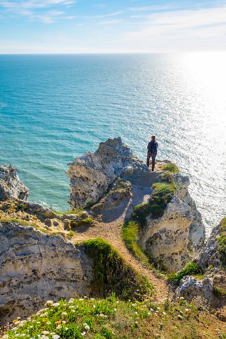 Young woman hiking on cliffs overlooking English Channel, Etretat, Normandy, France