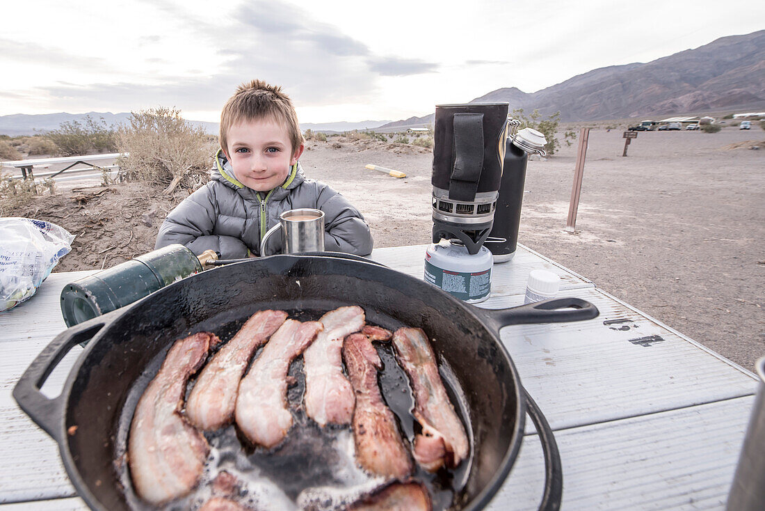 Boy smiling at bacon breakfast while camping in Death Valley National park, California, USA