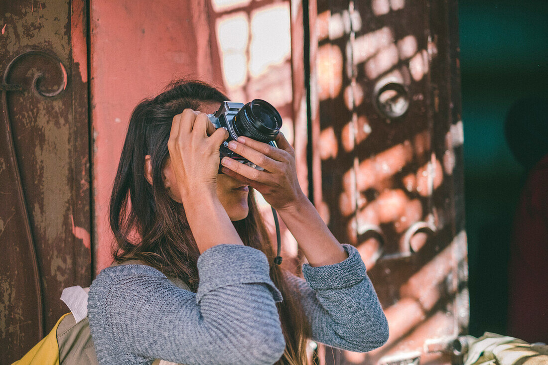 Mädchen, das Foto mit Weinlesekamera im Straßenmarkt von Marrakesch, Marokko macht