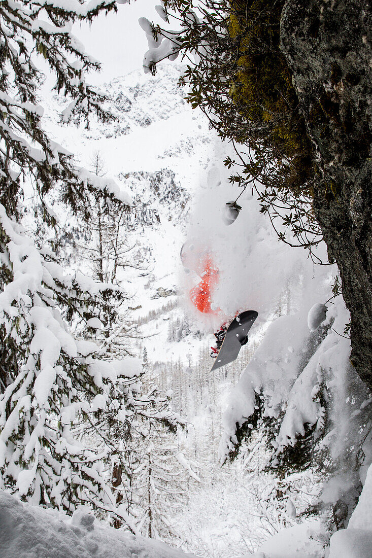 Ein Snowboarder springen von einer Klippe und fallen frischen Schnee