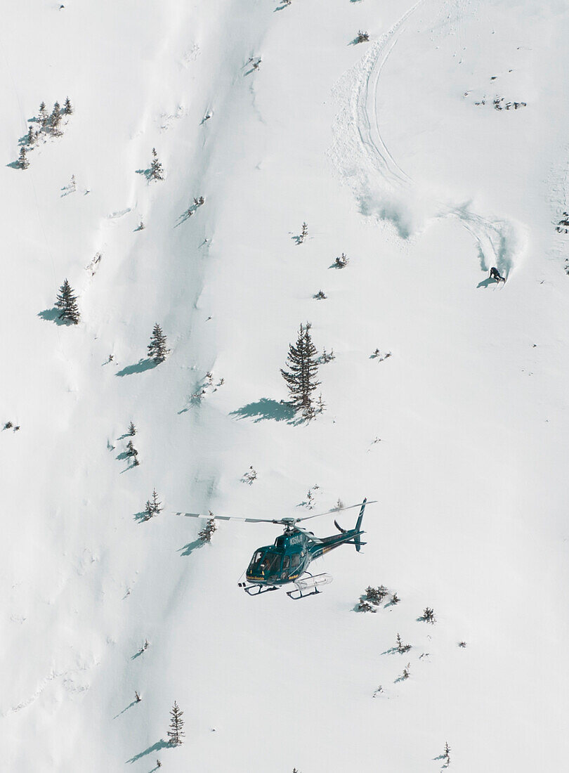 Hubschrauber, der über San Juan-Gebirgszug fliegt, wenn ein Skifahrer ein frisches Schnee-Pulver absteigt