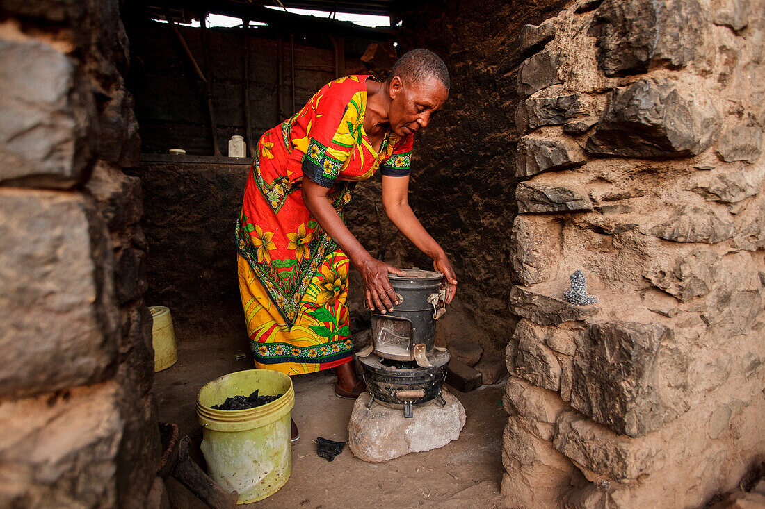 Die Solar-Schwester-Unternehmerin Julieth Mollel (61) bereitet sich auf ihr sauberes Kochtopf in ihrem Haus in der Nähe von Arusha, Tansania, vor. Julieth Mollel ist groß, als sie sagt, sie sei eine Solar Sister Entrepreneur und ihr Erfolg beim Verkauf de