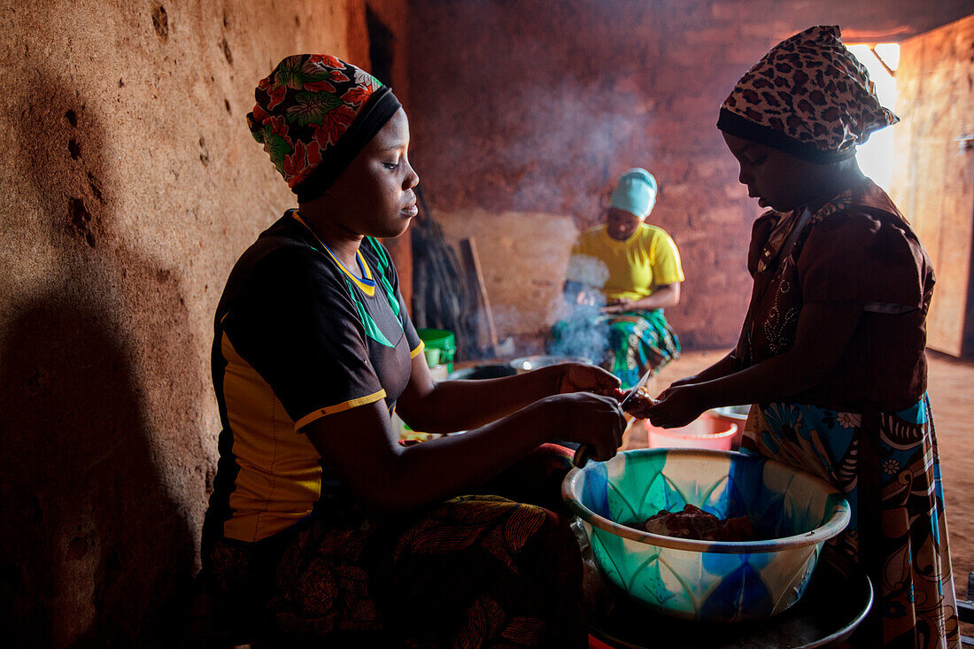 'Mforo, Tansania ein Dorf in der Nähe von Moshi, Tansania. Die Solar Sister Unternehmerin Fatma Mziray und ihre älteste Tochter Zainabu Ramadhani, 19 Koch Mittagessen in ihrem Küchenhaus mit einem sauberen Kochherd mit Holz und einem mit Kohle. Eine ihrer
