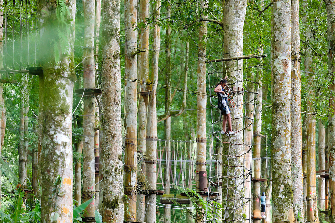 A girl ties into a zipline at a treetop Adventure Park, Bali, Indonesia
