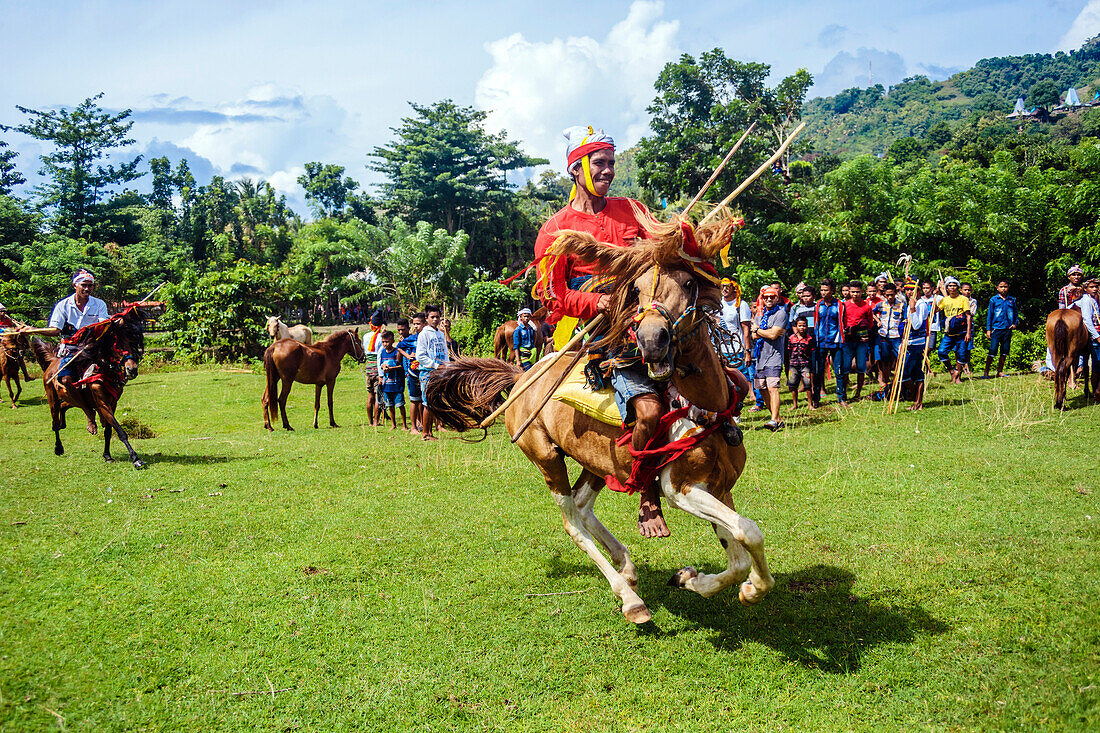 Young man wearing traditional costume riding horse and holding spear at Pasola Festival, Sumba island, Indonesia