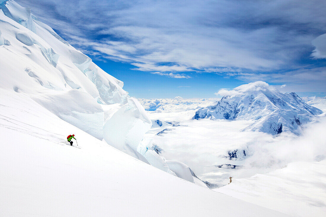 A Skier Is Descending A Snow Covered Glacier On Denali In Alaska With Mount Hunter In Background