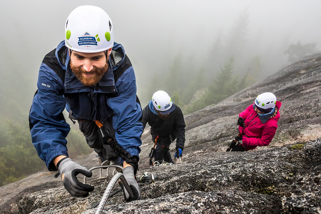 A man reaches for the metal rung while climbing the Via Ferrata in Squamish, British Columbia.