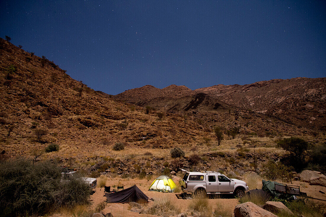 Tourist camp with tents and 4x4 car at night, Brandberg mountain, Damaraland, Namibia