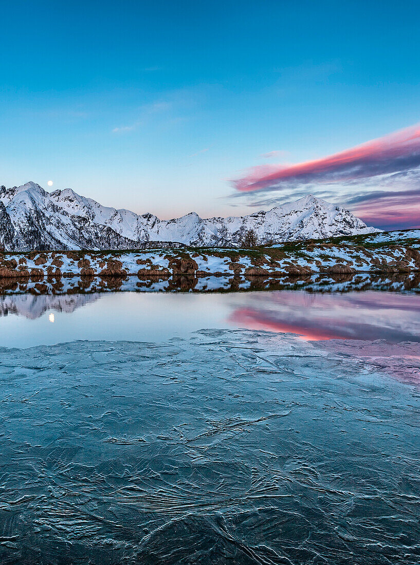 Thaw in alpine lake at dawn,the moon It reflects in the lake Gerola valley, Valtellina, lombardy, Italy,europe