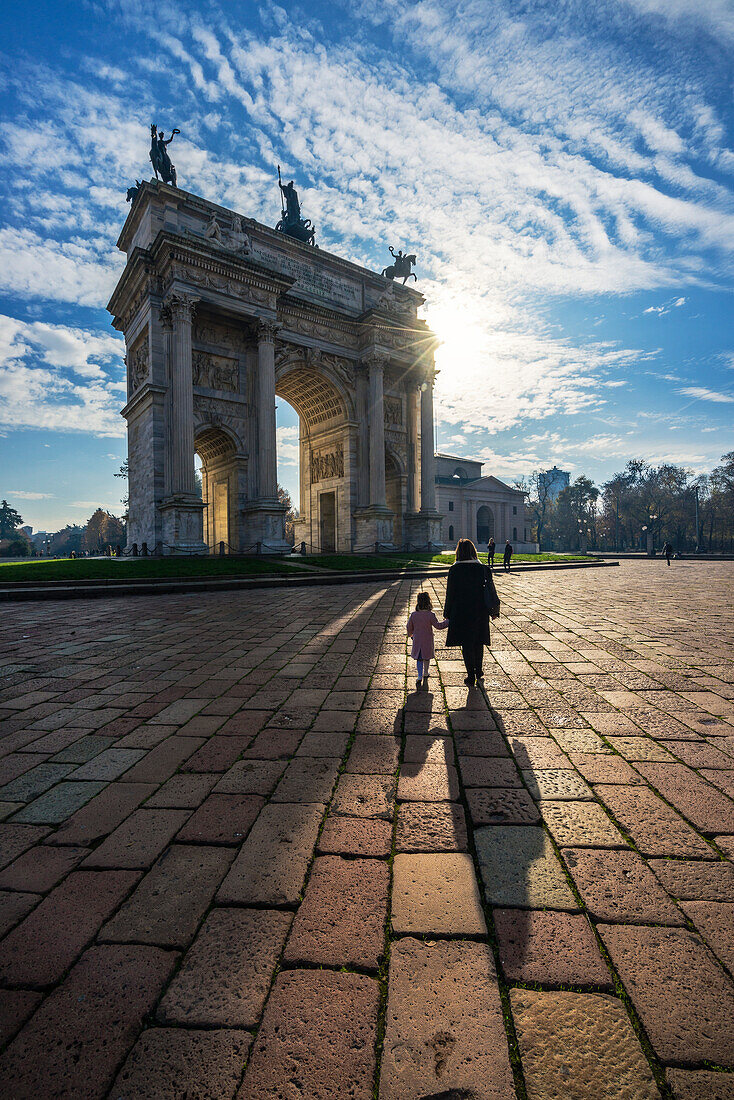 Milan, Lombardy, Italy, A woman walk with her child at the Arch of the peace square
