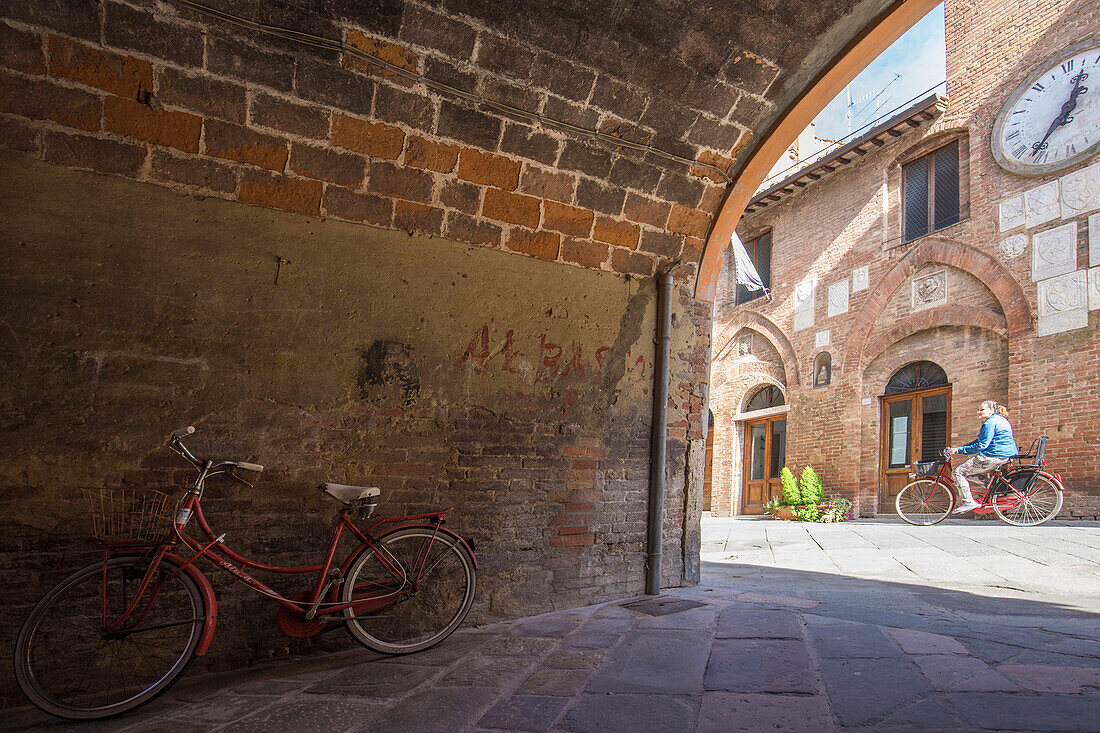 Blick auf das historische Zentrum von Buonconvento mit Durchgang eines Radfahrers, Buonconvento, Ombrone-Tal, Crete Senesi, Provinz Siena, Toskana, Italien, Europa
