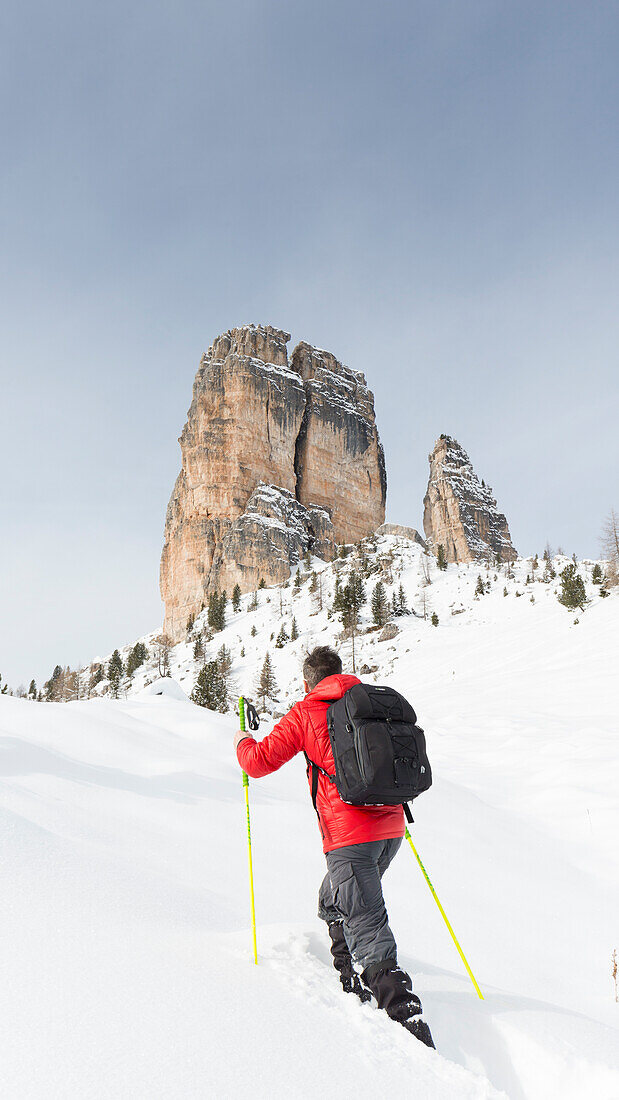 Blick auf einen Wanderer mit Schneeschuhen und den Cinque Torri im Hintergrund, Provinz Belluno, Venetien, Italien, Europa