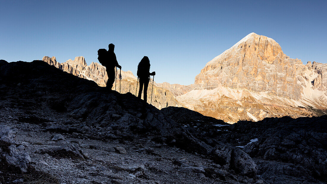 eine Ansicht von zwei Wanderern, die im Schatten stehen und zur Spitze Tofana, Belluno-Provinz, Venetien, Italien, Europa