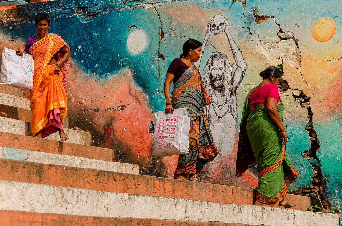 Varanasi, Uttar Pradesh, India, Women wearing traditional colorful saris waslk down the steps of the Ghats