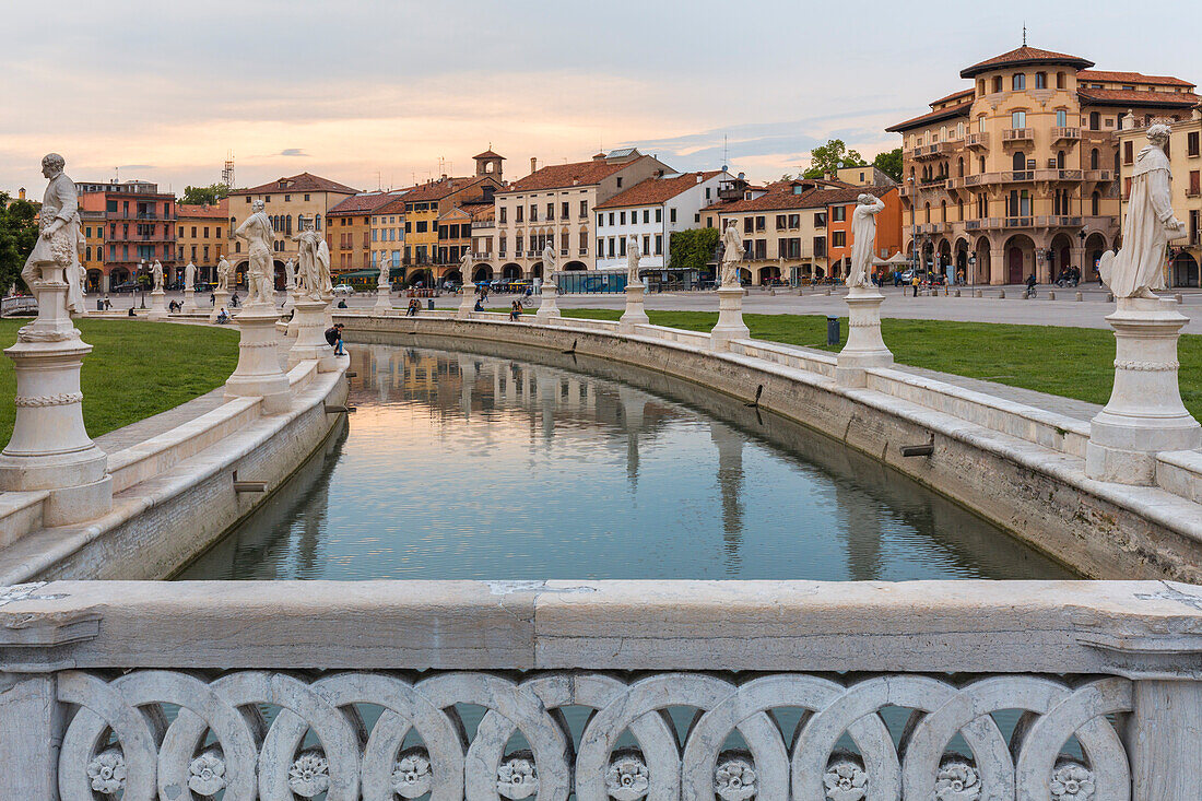 Ein Blick auf den Prato della Valle in Padua, Italien mit den Statuen entlang des Kanals spiegelt sich im stillen Wasser zusammen mit den umliegenden historischen Gebäuden, Veneto, Italien, Europa