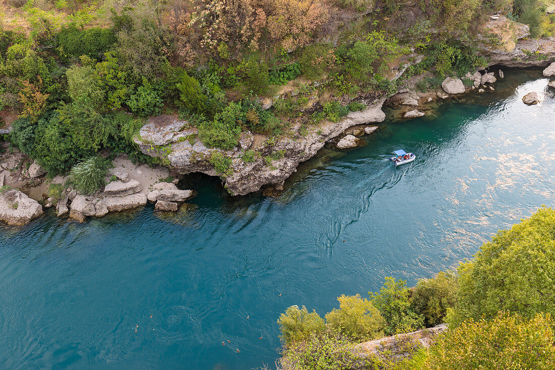 the turquoise waters of the Neretva River and a small boat for tourists, Mostar, Federation of Bosnia and Herzegovina