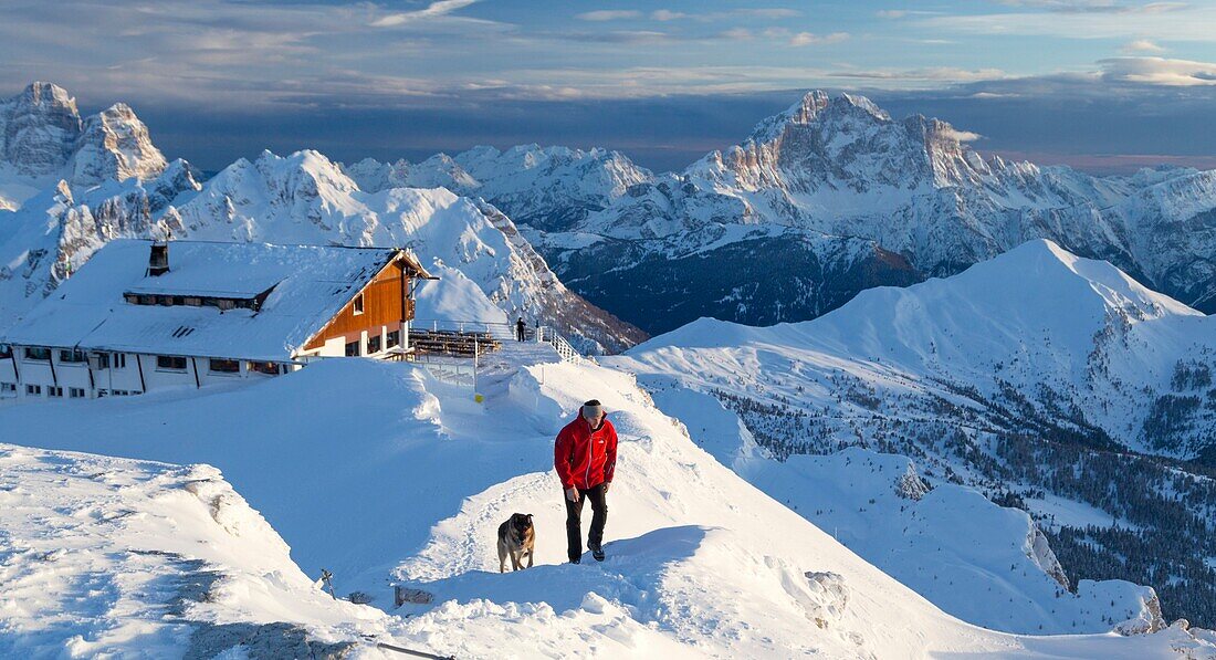 Wanderer mit Schäferhund auf dem schneebedeckten Kamm durch den hohen Gipfel des Monte Civetta Dolomiten Belluno Provinz Venetien Italien Europa