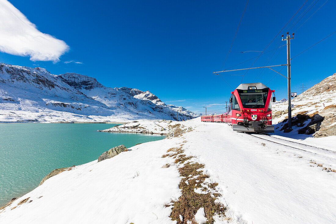 Bernina Express Zug im verschneiten Tal, umgeben vom Bianco Berninapass Kanton Graubünden Engadin Schweiz Europa