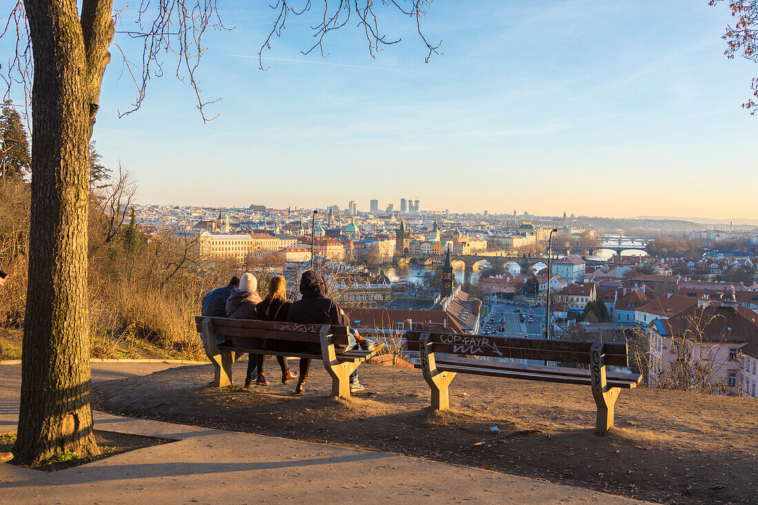 Menschen auf einer Bank bewundern die historischen Gebäude und Brücken auf Moldau Fluss bei Sonnenuntergang Prag Tschechische Republik Europa
