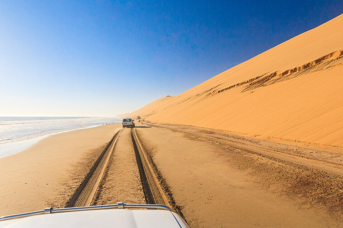 Jeep on the coast between sand dunes and the Atlantic Ocean Walvis Bay Namib Desert Erongo Region Namibia Southern Africa