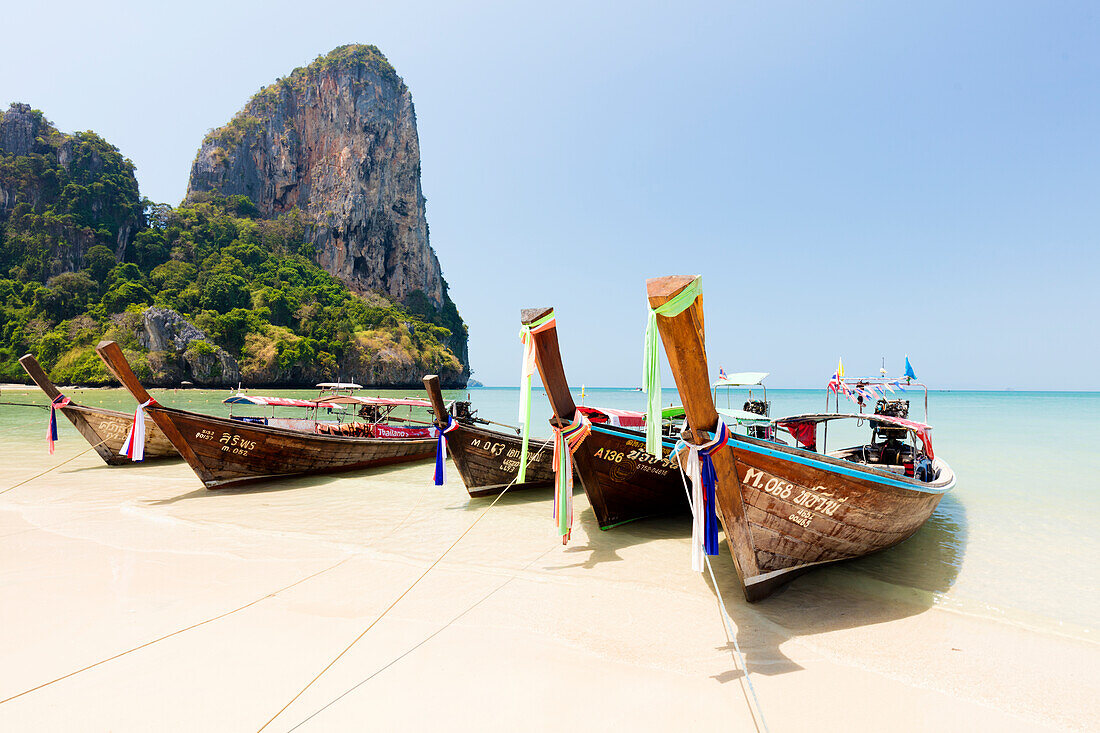Traditionelle Longtail-Boote vertäut von Railay Beach mit Kalksteinfelsen im Hintergrund, Ao Nang, Krabi, Thailand, Südostasien, Asien