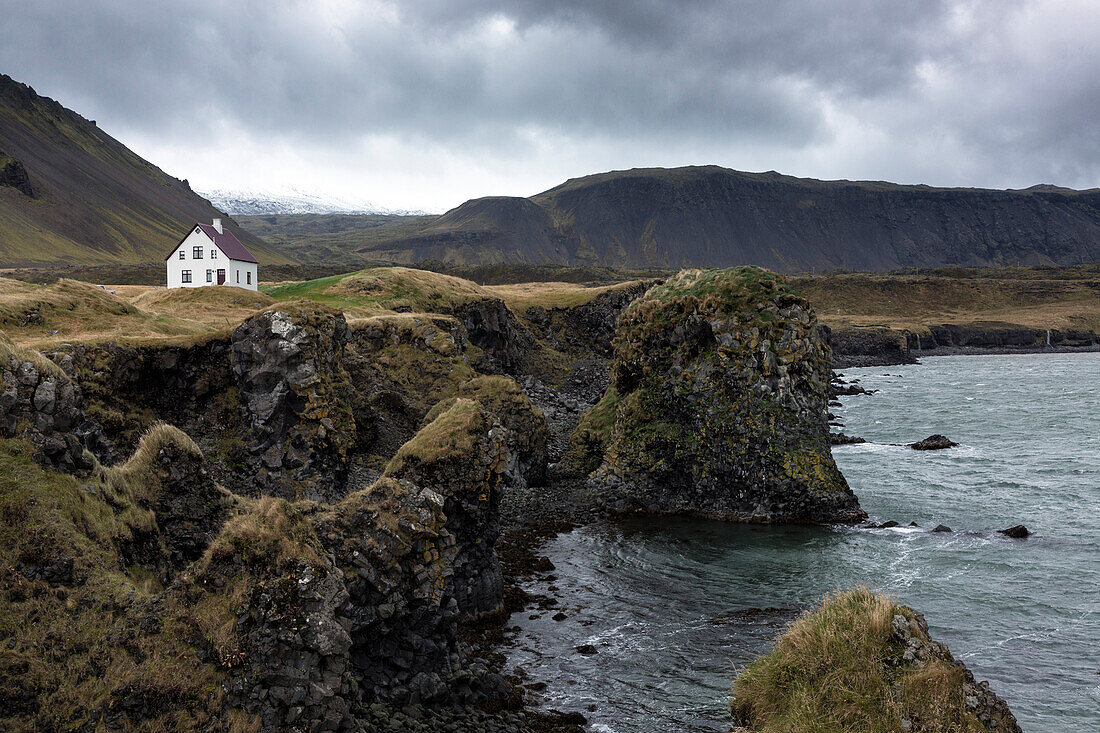 Einsames weißes Haus unter den Meerestapel und Berge bei Arnastapi, Snaefellsnes Halbinsel, Island, Polargebiete