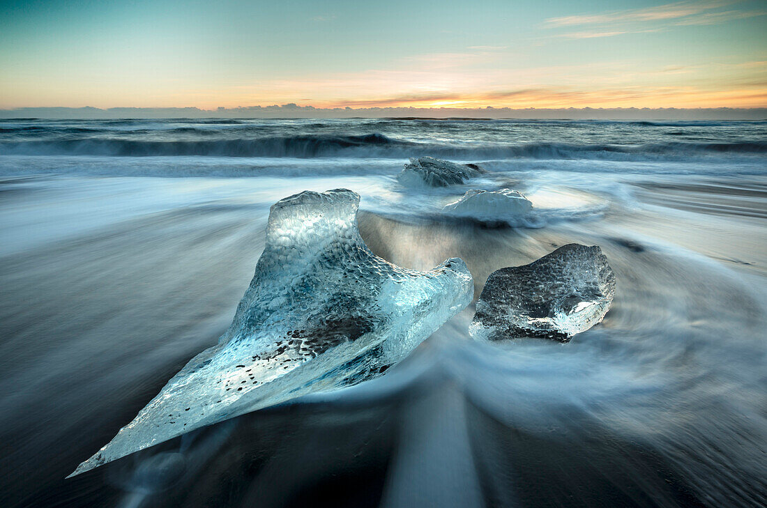 Pieces of glacier ice washed up on black volcanic sand beach at sunrise, near Jokulsarlon Glacial Lagoon, South Iceland, Polar Regions