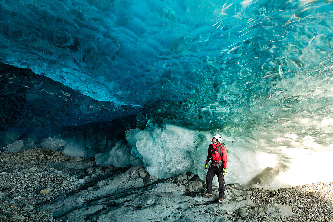 Höhlenführer mit Schutzhelm in einer der Eishöhlen unter dem Vatnajokull-Gletscher, Südisland, Polarregionen