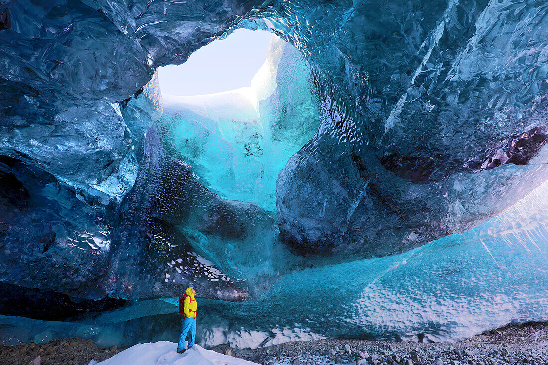 Inside ice cave under the Vatnajokull Glacier, with cave guide looking up to hole in cave roof, near Jokulsarlon, South Iceland, Polar Regions