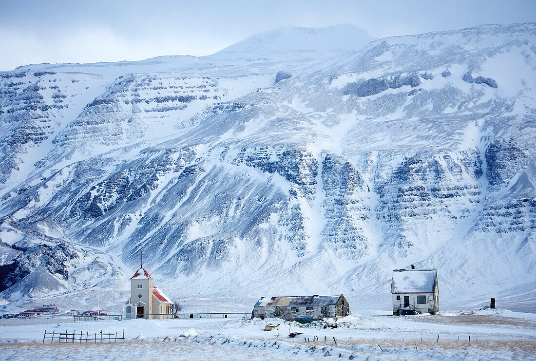 Kirche und abgelegener Bauernhof gegen Schnee bedeckten Berge, Winternachmittag auf der Straße zur Snaefellsnes-Halbinsel, Island, polare Regionen