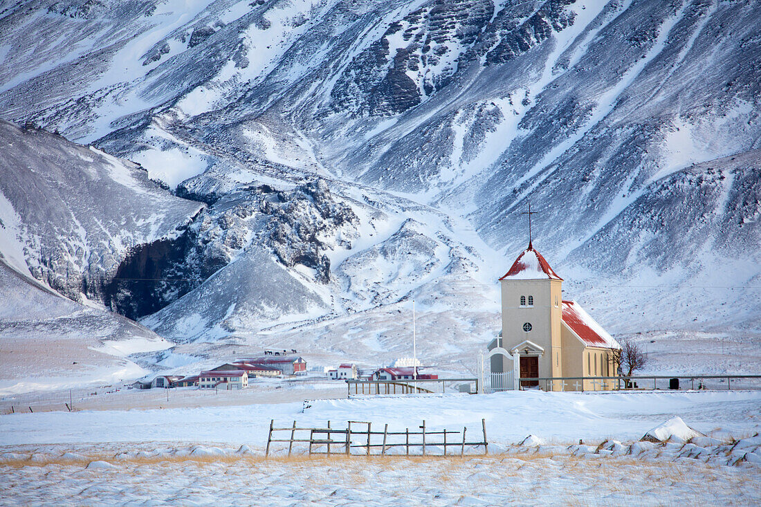 Kirche und abgelegener Bauernhof gegen Schnee bedeckten Berge, Winternachmittag auf der Straße zur Snaefellsnes-Halbinsel, Island, polare Regionen