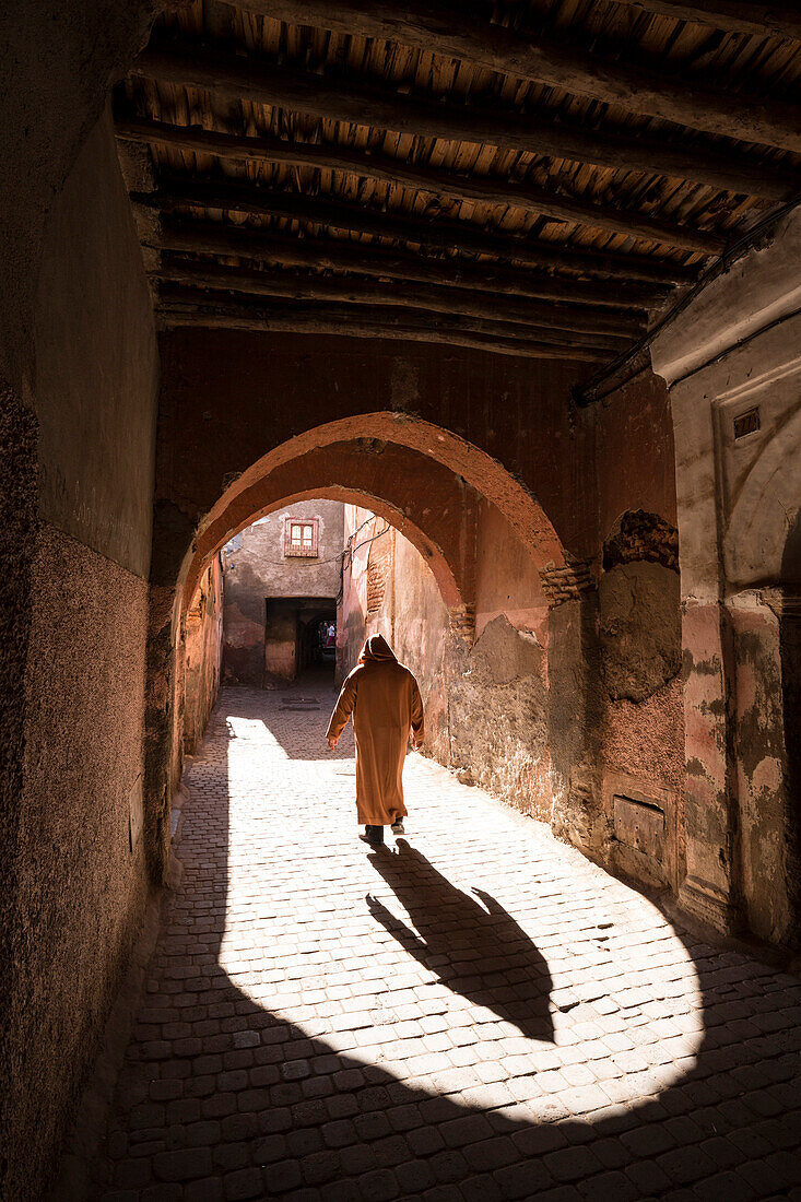 Local man dressed in traditional djellaba walking through archway in a street in the Kasbah, Marrakech, Morocco, North Africa, Africa