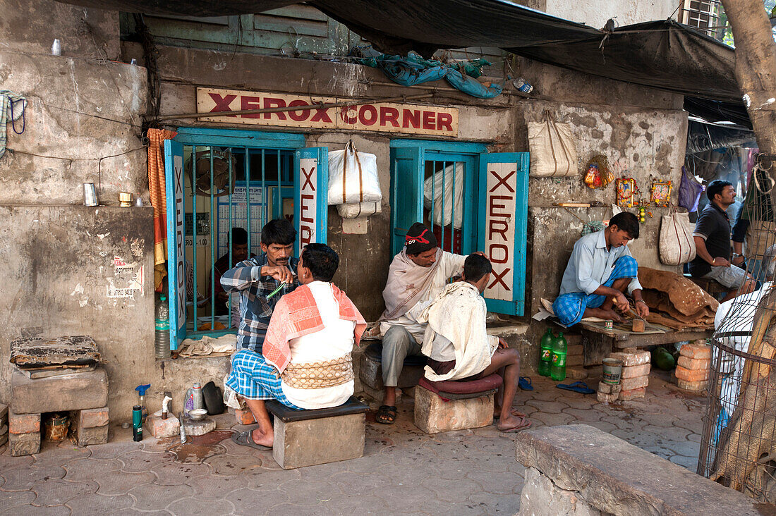 Barbers cutting hair and shaving men, and tobacco wallah, in street stalls outside Xerox shop in Dalhousie Square area of Kolkata ,Calcutta, West Bengal, India, Asia