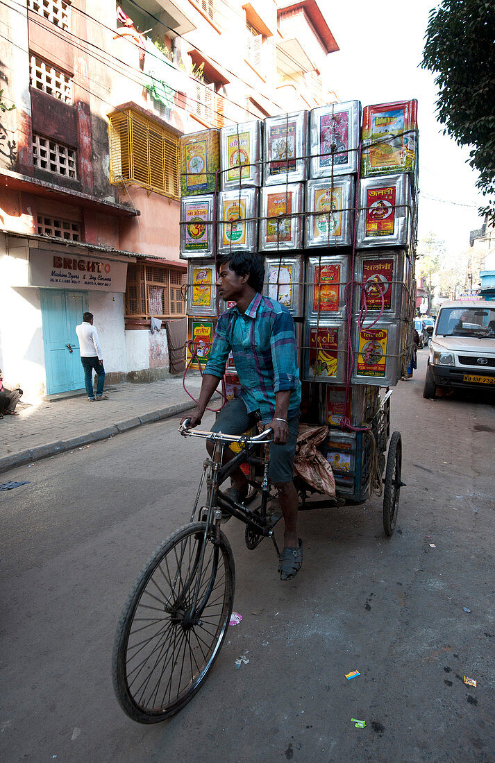 Piled up empty oil tins, being carried by cycle rickshaw to be recycled and used for slum house walls, Kolkata ,Calcutta, West Bengal, India, Asia