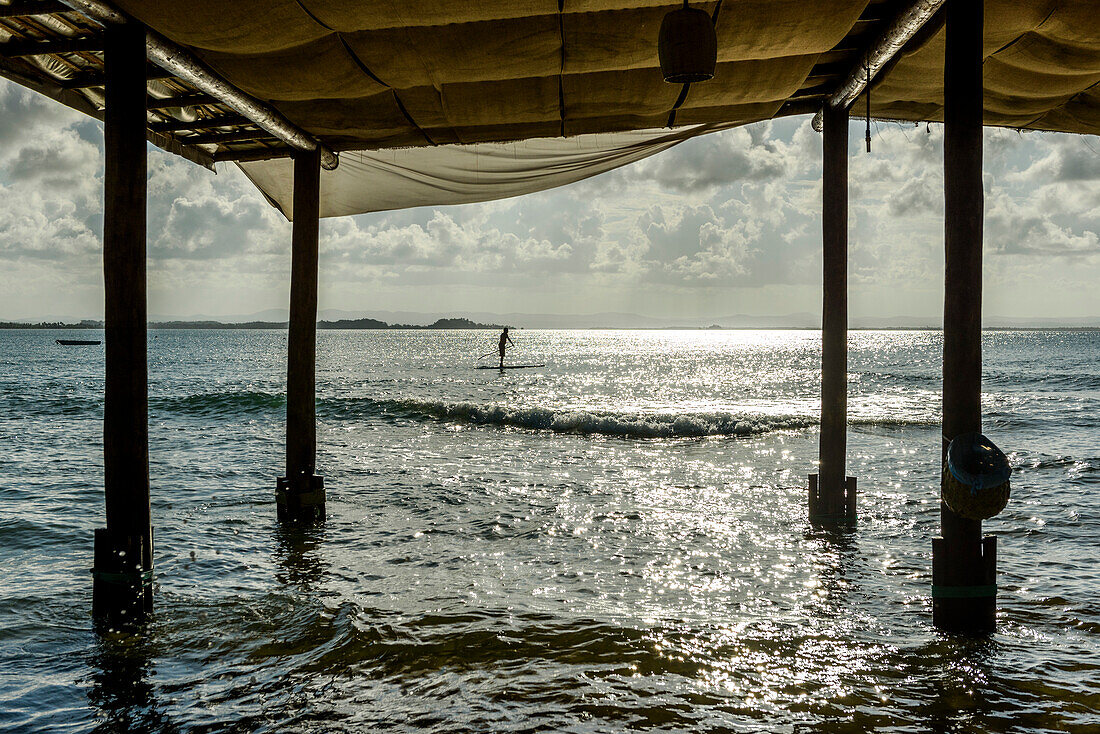 Man riding his stand up paddle board during sunset in tropical south Bahia, Peninsula de Marau, Brazil