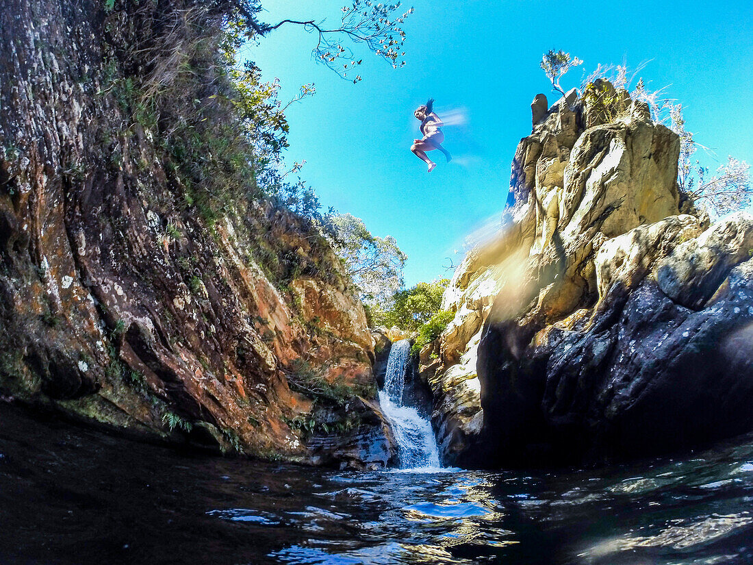 Abenteuerliche Frau, die vom Felsen in Fluss in Serra do Cipo Nationalpark, Minas Gerais, Brasilien springt