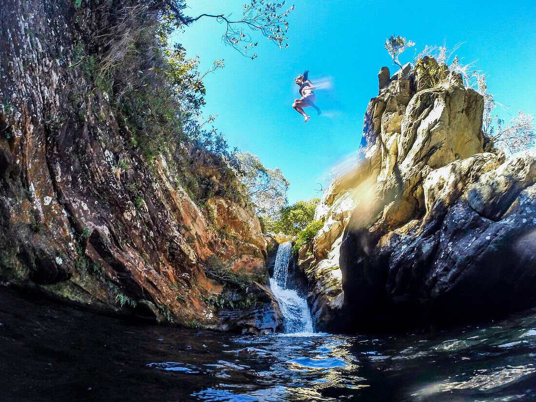 Adventurous woman jumping from rock into river in Serra do Cipo National Park, Minas Gerais, Brazil