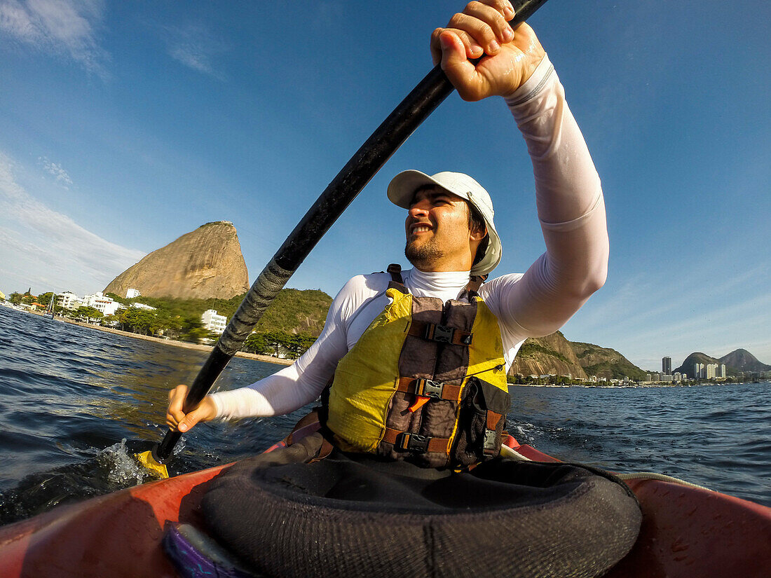 Man Kayaking in Guanabara Bay mit Zuckerhut auf der Rückseite, Rio de Janeiro, Brasilien
