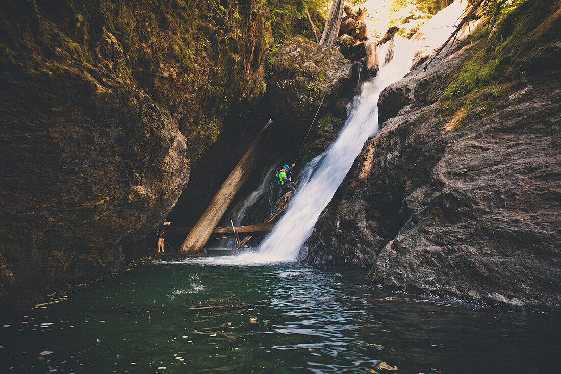Man rappelling off waterfall while canyoneering in Deneau Creek, Hope, British Columbia, Canada