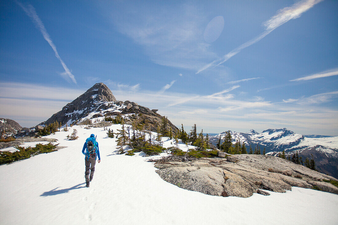 Photograph with rear view of male backpacker hiking to Needle Peak in winter, Hope, British Columbia, Canada