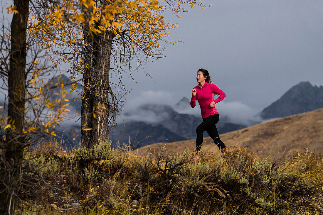 Female runner jogging against mountain range, Wyoming, USA